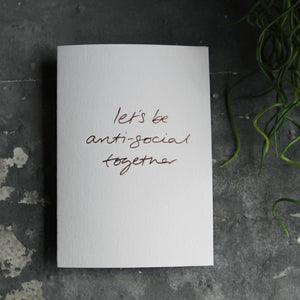 this hand foiled luxury white card says Let's Be Anti Social Together on the front in rose gold foil