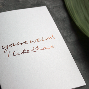 this luxury card says 'you're weird i like that' and is handwritten and hand printed in rose gold foil